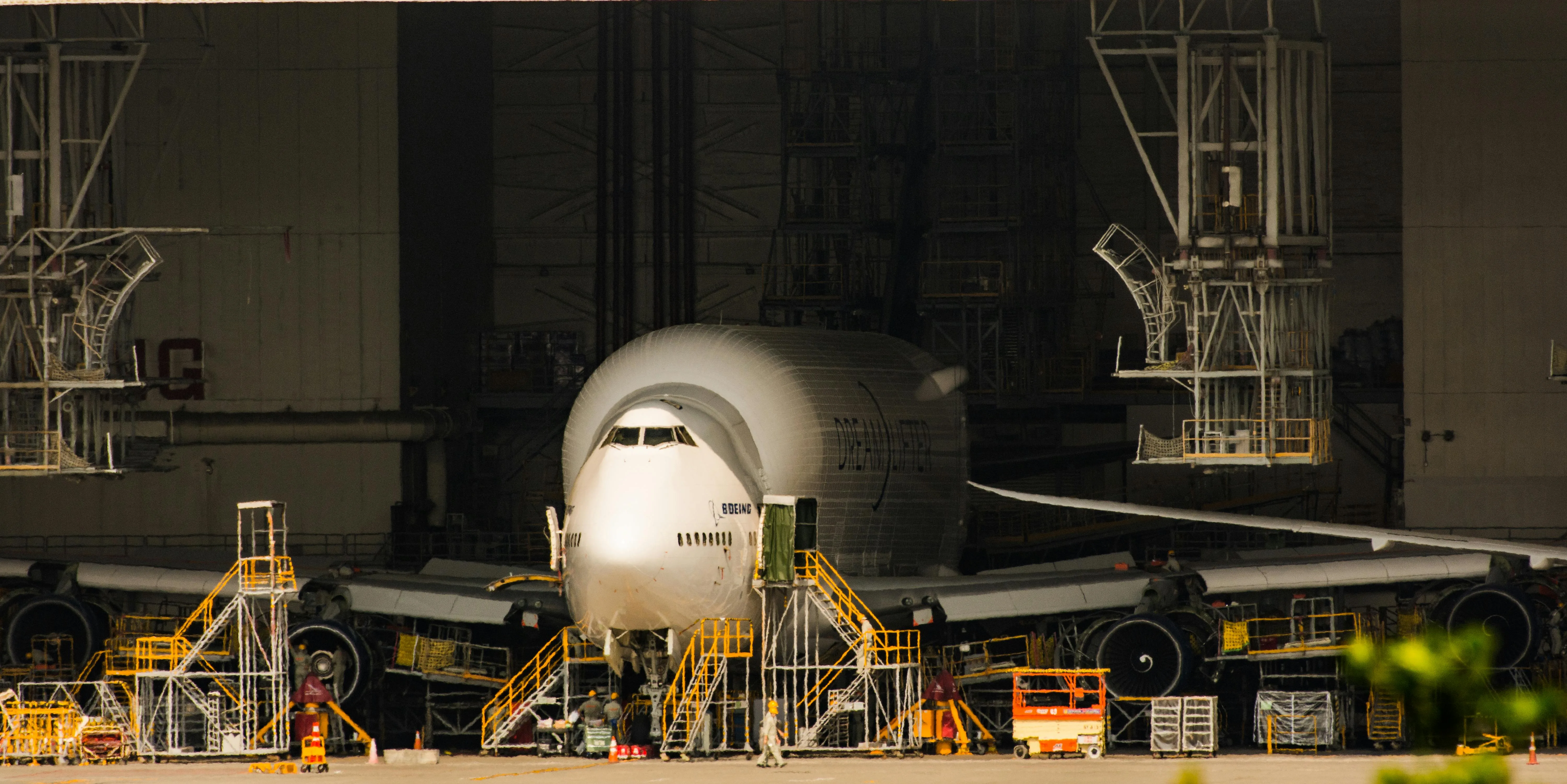 An aircraft docked in a hangar with engineers nearby